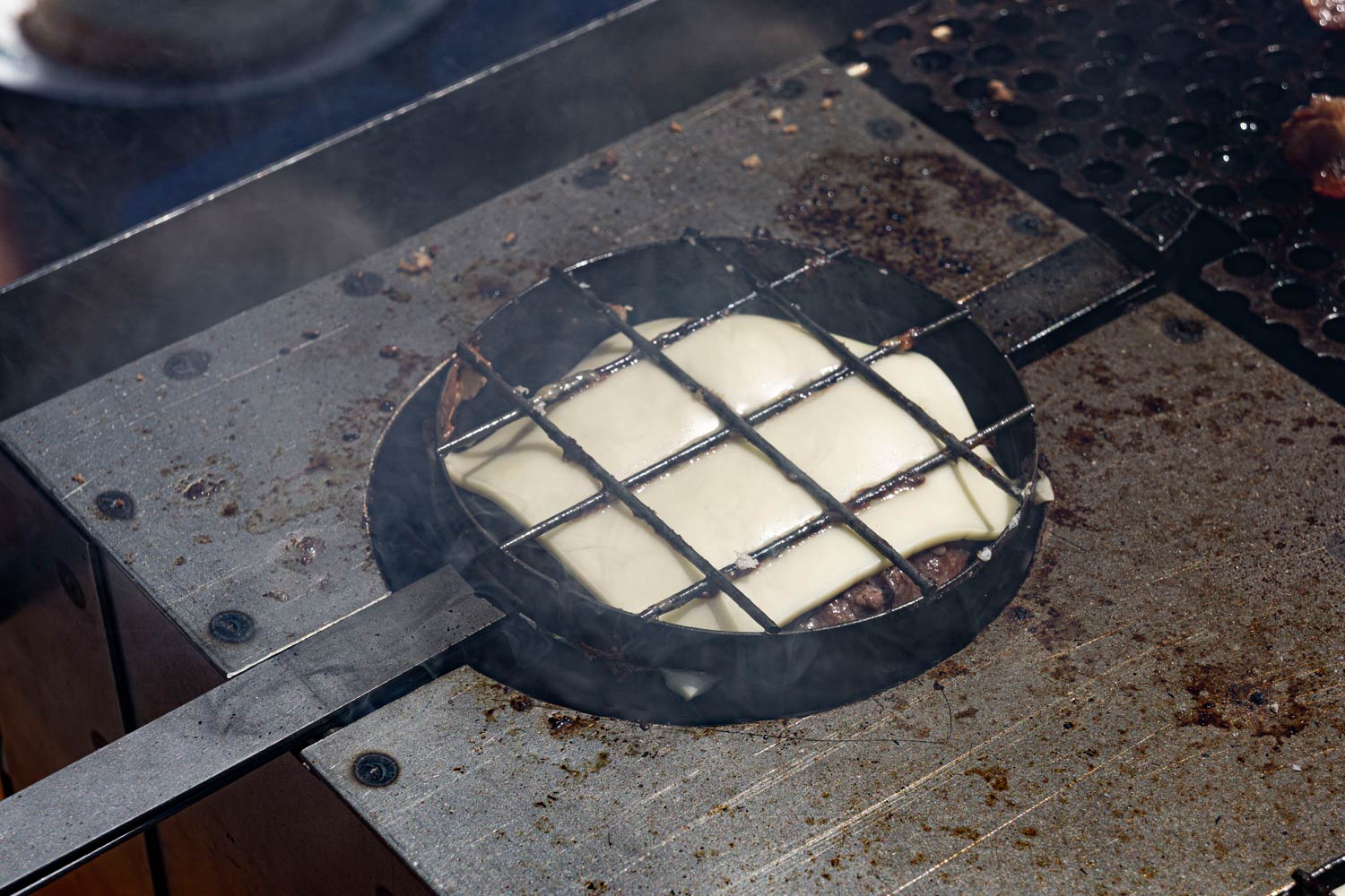 closeup of a cheeseburger in the macking on the burger grill qb